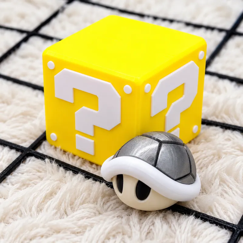 Cubo amarelo com pontos de interrogação brancos e pequeno casco cinza à frente.